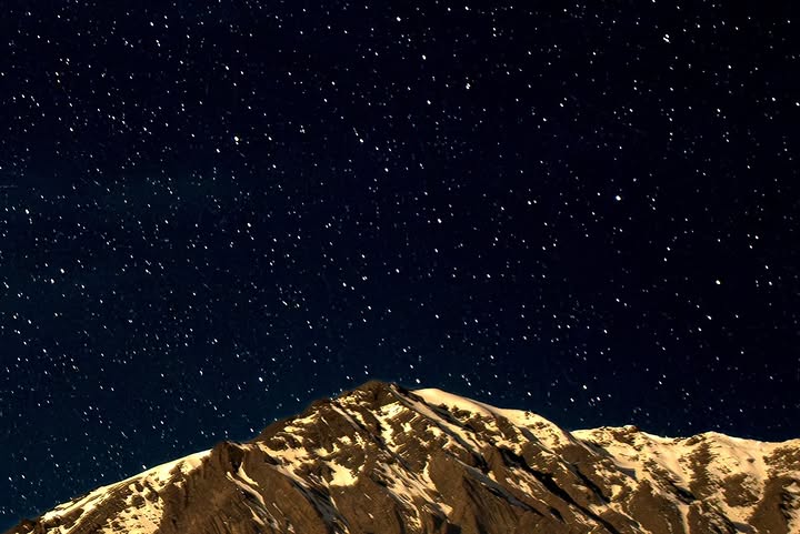 Stars over moonlit, snow-capped mountain peaks at night (3/3)